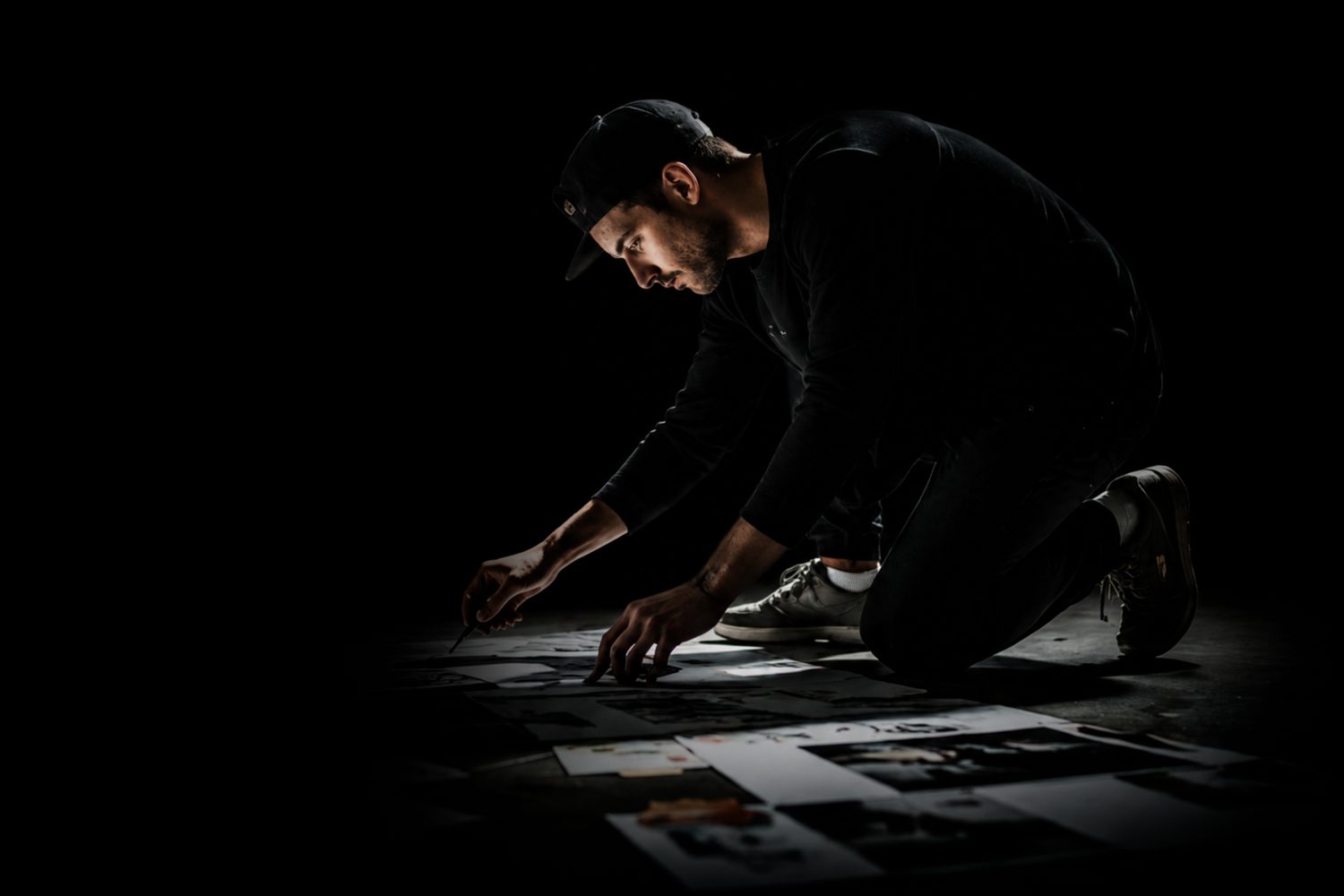 A creative on one knee arranging printed layouts on the floor