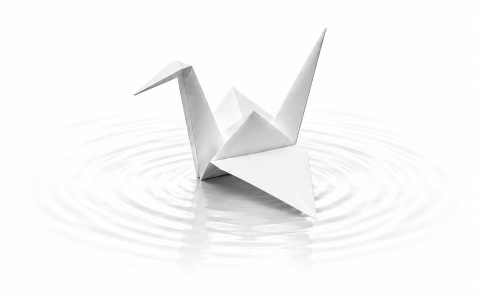 A white paper crane resting on still water